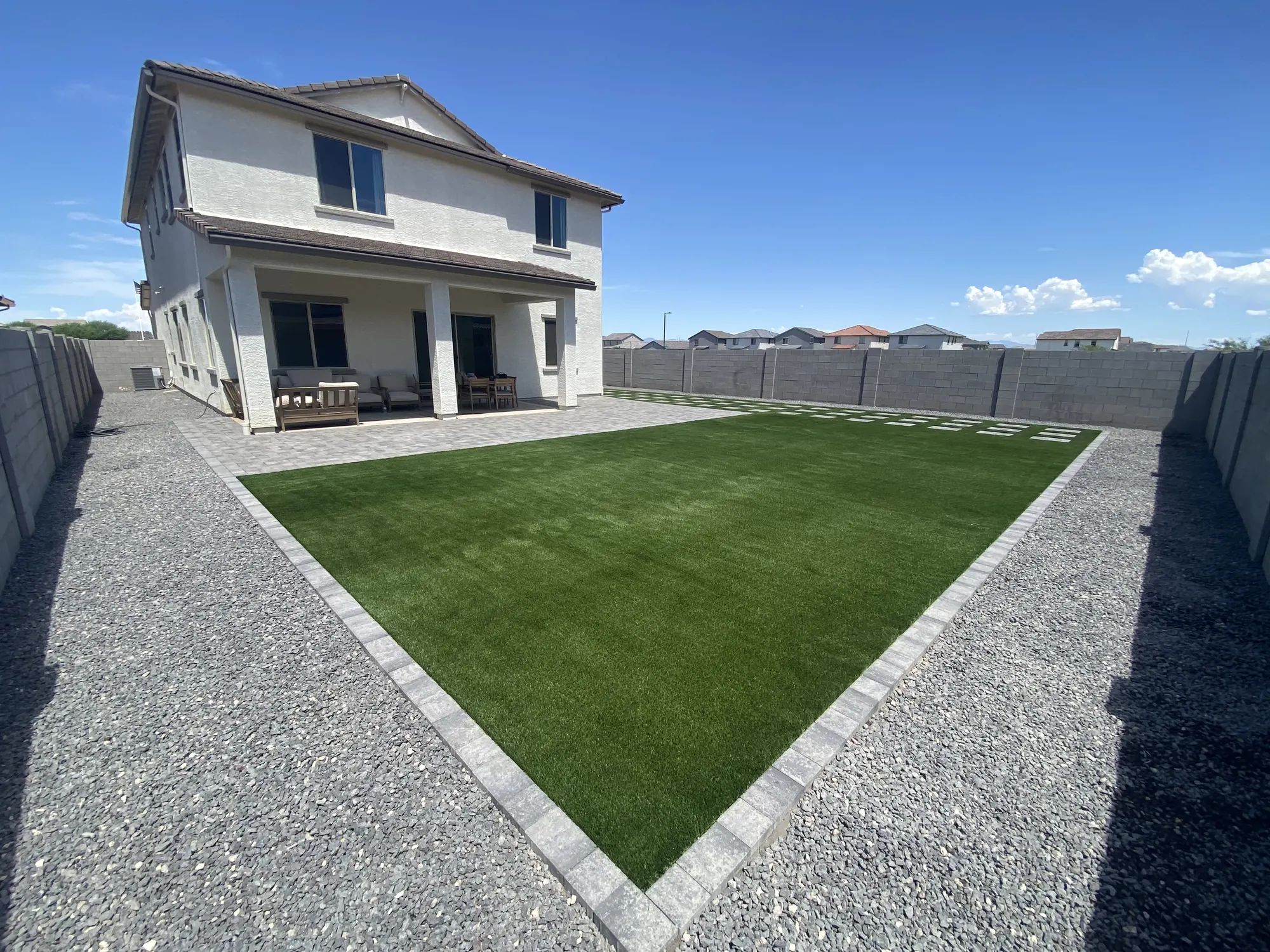 Completed Turf Time AZ backyard with a large artificial turf lawn and paver border
