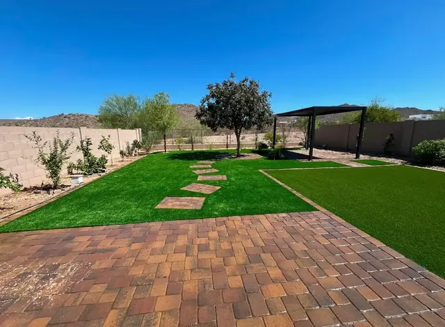 Backyard with artificial turf, paver patio, stepping stones and a pergola