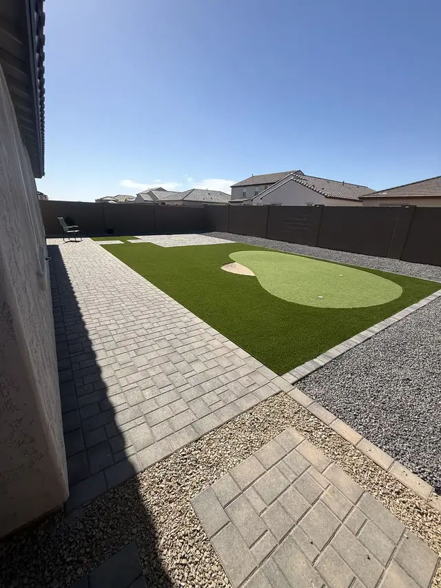 Backyard putting green with paver walkway and rock