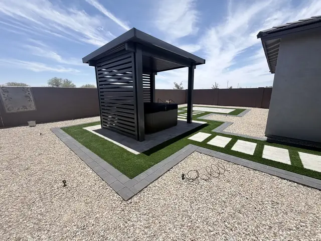 Modern black cabana on a paver pad with artificial turf and gravel