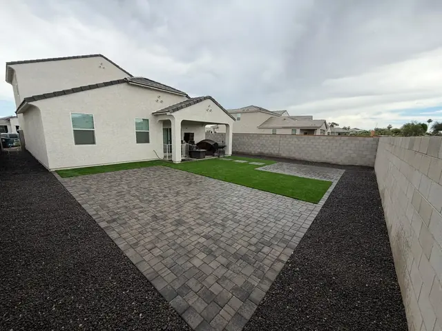 Charcoal paver patio with artificial turf and black landscape rock