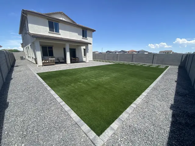 Large artificial turf lawn with paver border and rock