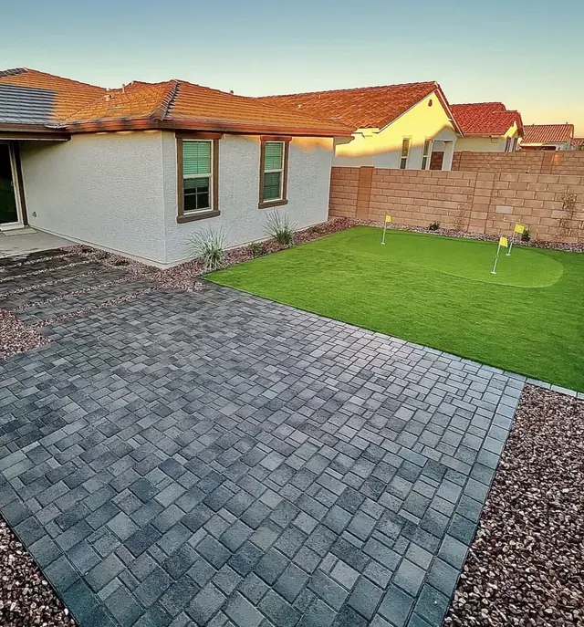 Slate-toned paver patio next to a rectangular turf putting green
