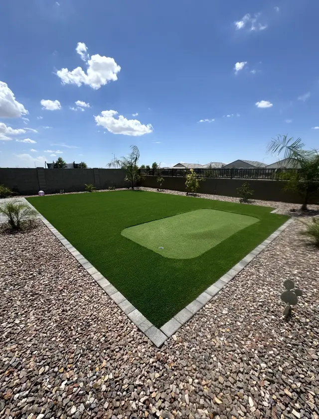 Large artificial turf lawn with a putting green and landscape rock border