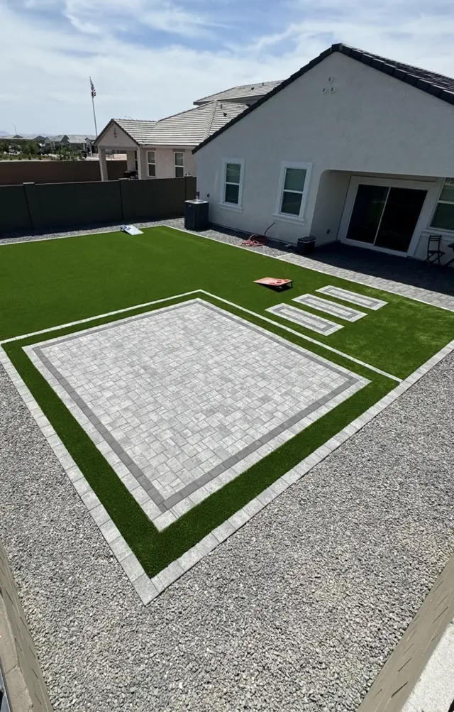 Light paver patio and stepping pads set within an artificial turf lawn
