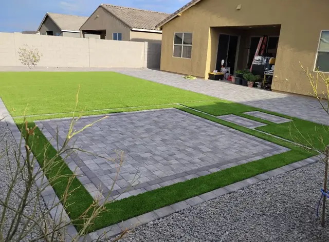 Gray paver patio and stepping pads surrounded by artificial turf