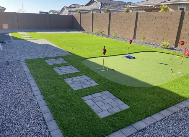 Turf putting green with square paver stepping pads and a paver patio