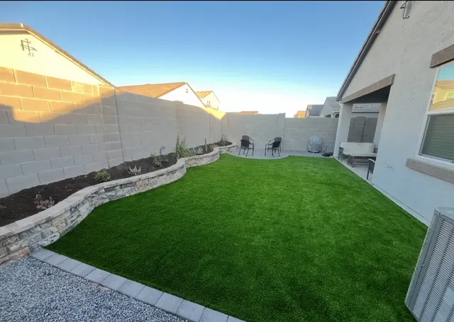 Artificial turf lawn beside a curved stacked-stone planter wall
